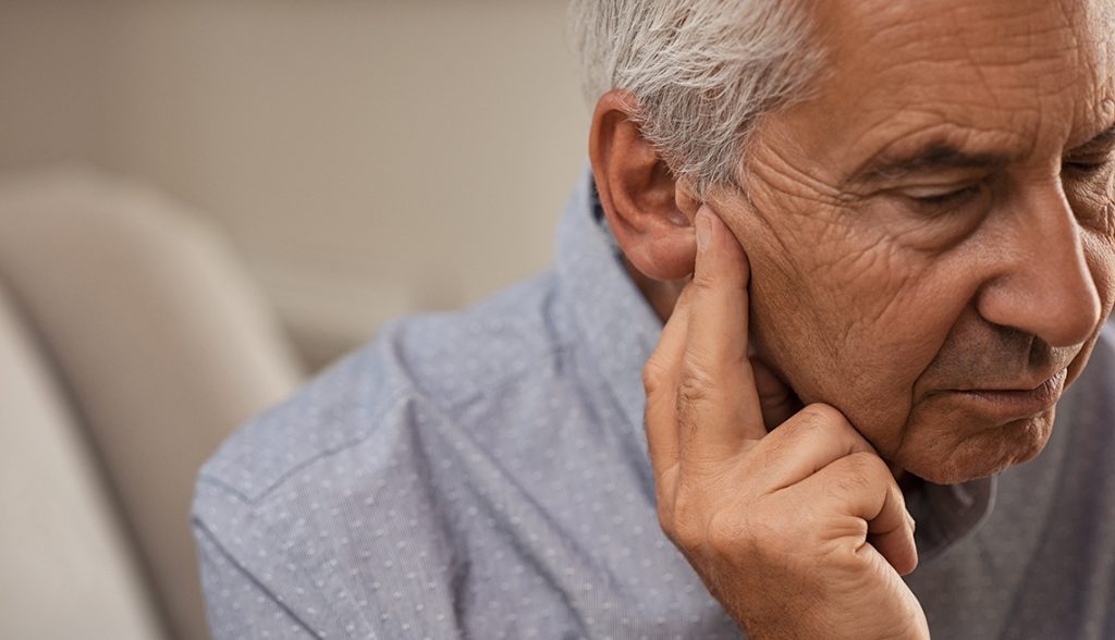Un hombre mayor con su mano cerca de su oído